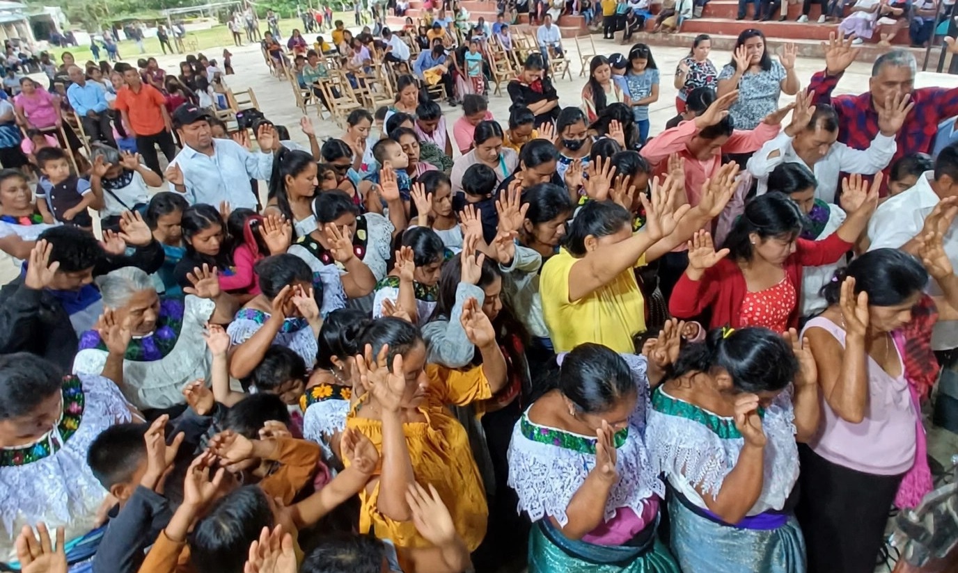 Night gathering in Chiapas with hands raised in prayer