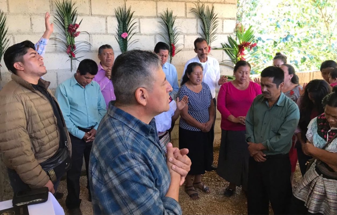 Angel Romero praying with a group outdoors